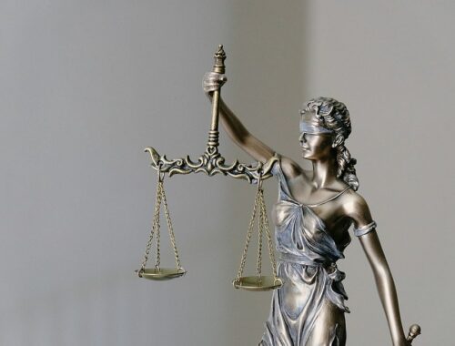 A bronze statue of Lady Justice holding a set of scales, symbolizing fairness and balance.