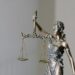 A bronze statue of Lady Justice holding a set of scales, symbolizing fairness and balance.