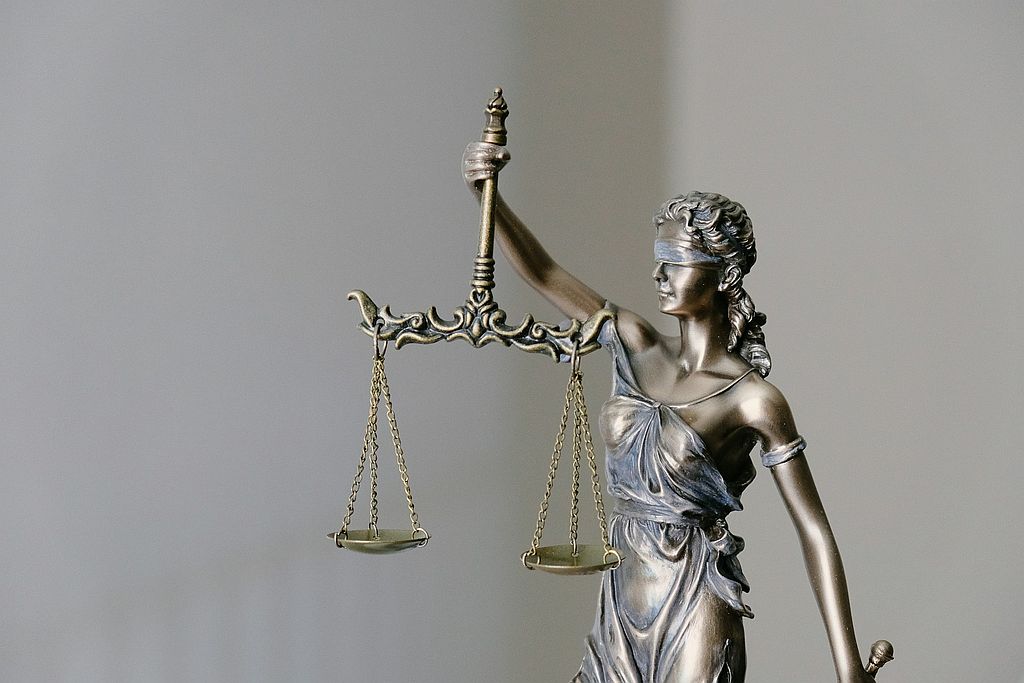 A bronze statue of Lady Justice holding a set of scales, symbolizing fairness and balance.